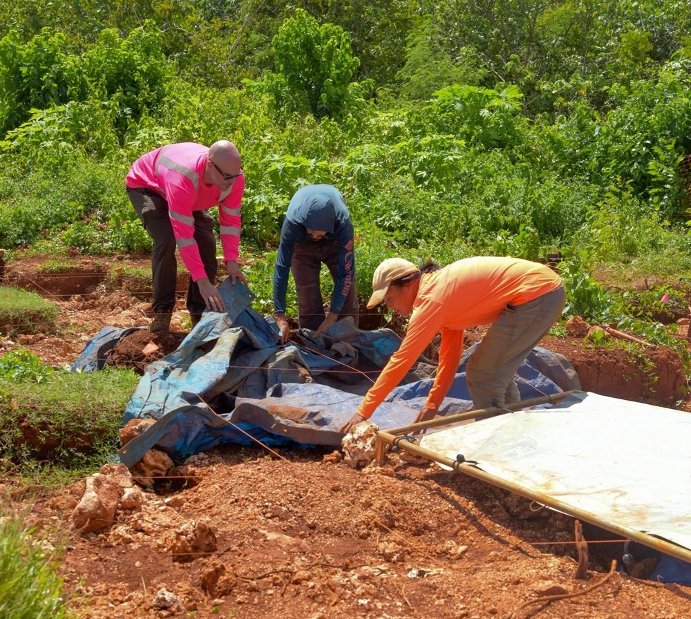 Archeologists work carefully around ancient remains found on an excavation site at Camp Blaz in April 2023.